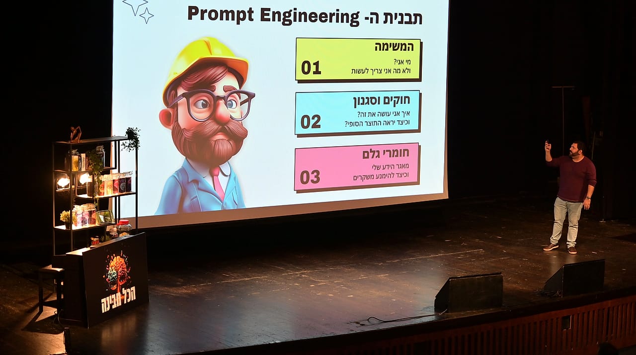 בן רוטנברג מרצה על במה גדולה בכנס הכל מבינה, על המסך תבנית ה-Prompt Engineering